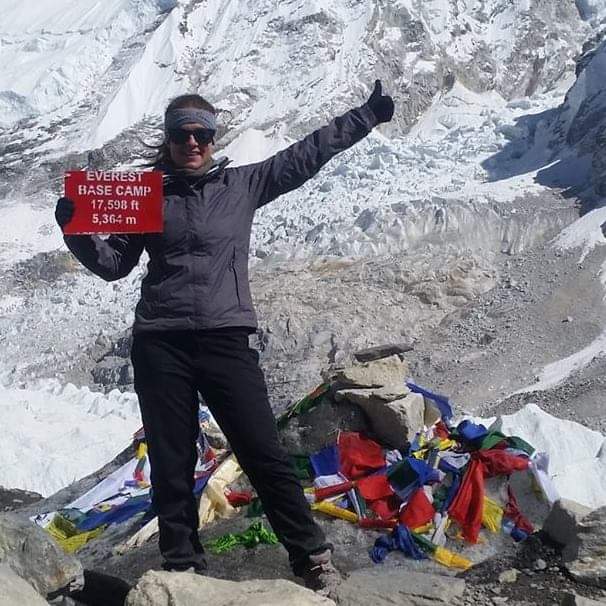 IAA communications officer, Lisa Nelson, standing triumphantly at Everest Base Camp